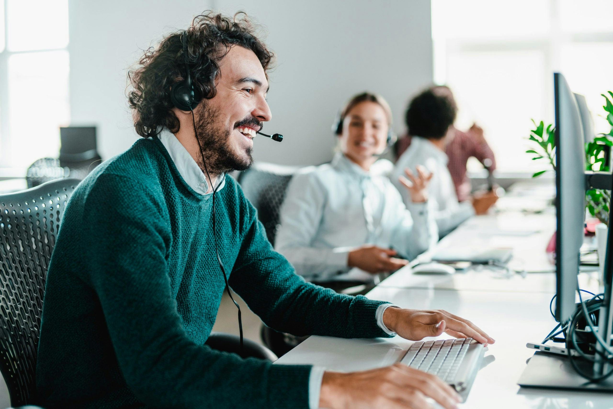 Man with beard and green sweater working in contact center